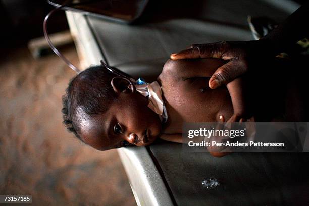 Mother holds her hand on her sick child on December 5, 2005 in Dubie Hospital, in Dubie, Katanga Province in Congo, Democratic Republic of the Congo....