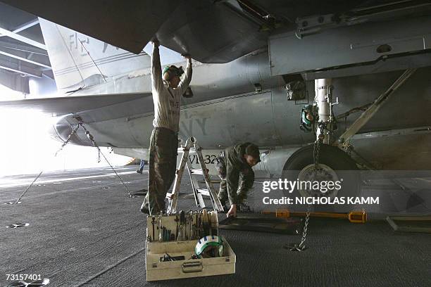 This photo dated 06 March 2003 shows mechanics repairing an F-14 Tomcat in the hangar bay of USS Harry Truman in the eastern Mediterranean. The...