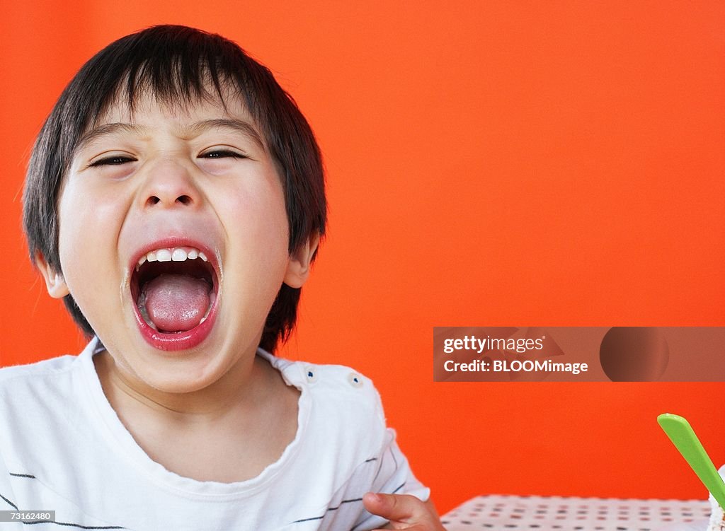 Asian young boy eating birthday cake