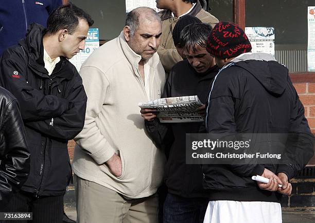 Local residents read the headlines of an evening newspaper in Jackson Rd, Birmingham after a series of anti-terror dawn raids across the city...