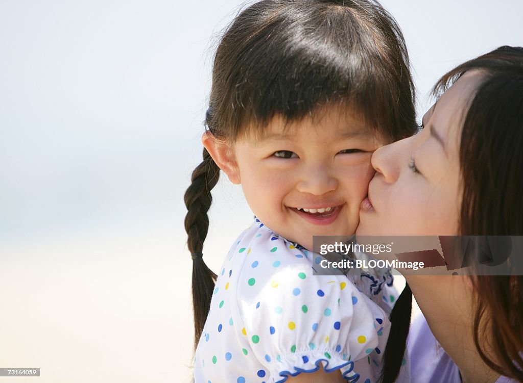 Mother kissing daughter smiling