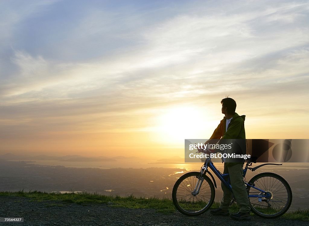 Man looking at away scenery from top of mountain ,riding bicycle