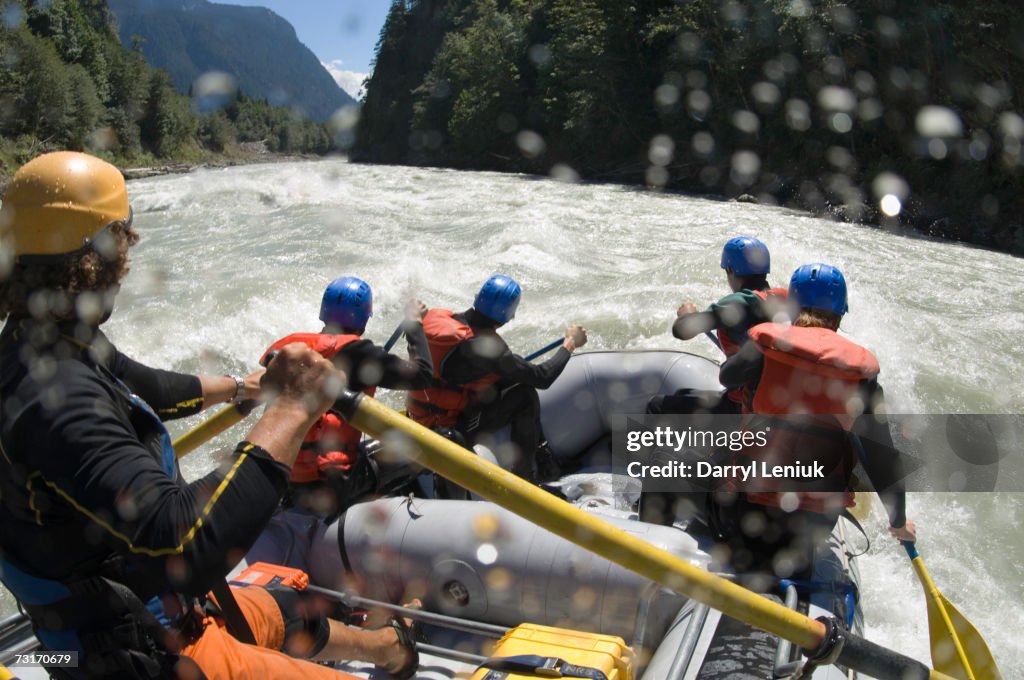 People whitewater rafting, rear view