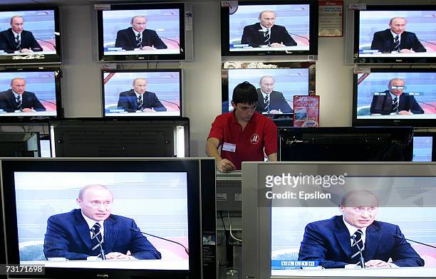 Shop assistant watches TV screens in a shop during the broadcasting of Russian President Vladimir Putin's annual address to Russian and foreign media...