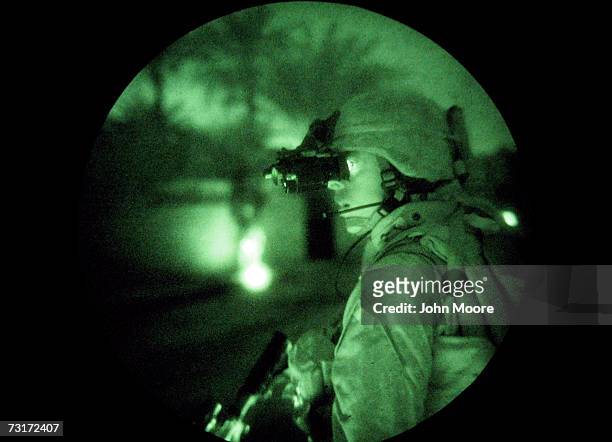 Using night vision goggles a U.S. Marine looks down a dark street while on a search operation for insurgents in the early hours of February 1, 2007...