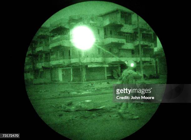 Marine illuminates a building using an infrared laser only visible using night vision goggles while on a search operation for insurgents in the early...