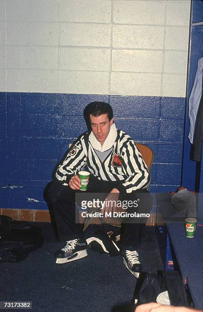 American ice hockey linesman Pat Dapuzzo sits on a bench in the locker room and drinks from a paper cup, December 1991.