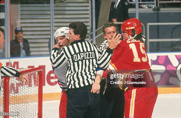 American ice hockey linesman Pat Dapuzzo restrains Kris King of the New York Rangers while a second linesman holds onto Neil Sheehy of the Calgary...