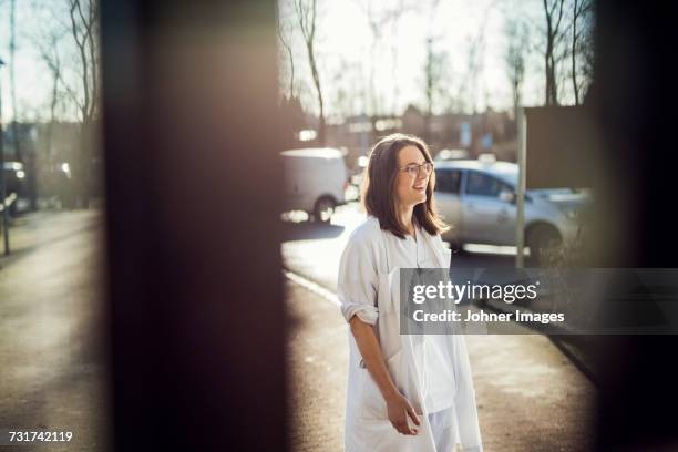 female doctor standing in parking - back lit doctor stock pictures, royalty-free photos & images