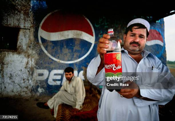 The owner of this restaurant of fresh fish " Adi Za? " drinks and shows a Mecca-Cola bottle on July, 2004 in Afghanistan.