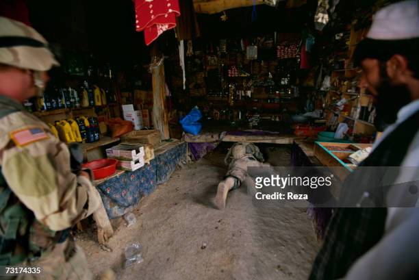 This soldier crawls under a bazaar stall in the Pashtun tribal zone of Waziristan on July, 2004 in Afghanistan.