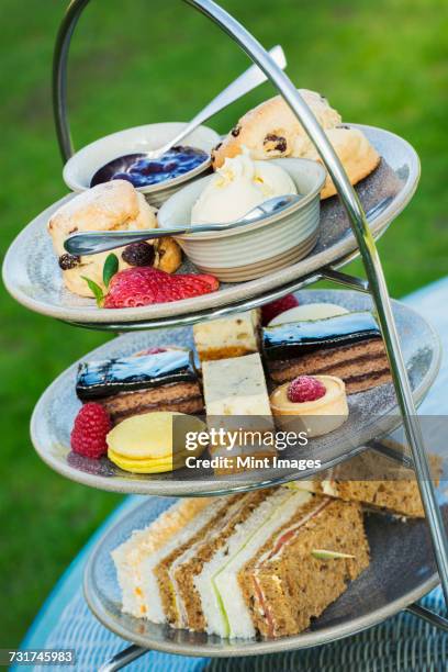 close up of a cake stand with a selection of cakes and sandwiches, traditional afternoon tea. - cakestand stock-fotos und bilder