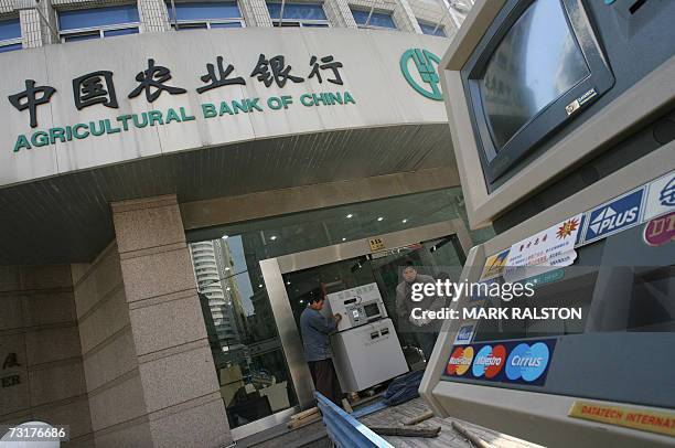 Workmen remove banking machines including ATM's from a branch of the Agricultural Bank of China in Shanghai 02 February 2007. A senior official from...