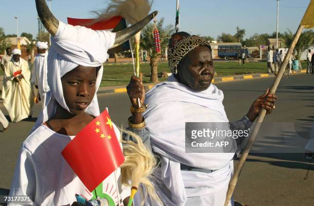 Member of a Sudanese traditional musical band carries a Chinese flag as men and women welcome Chinese President Hu Jintao on the airport road in...