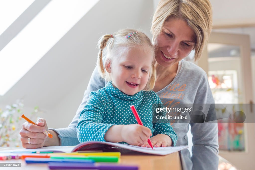 Mère aidant sa fille à colorier à la maison