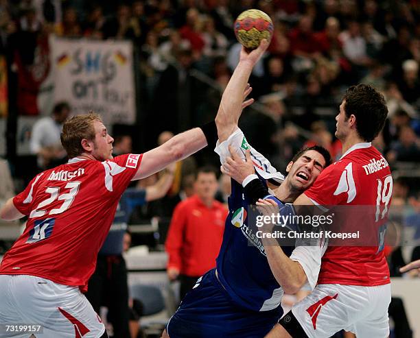 Joachim Boldsen and Jesper Noddesbo of Denmark tackle Nikola Karabatic of France during the IHF World Championship third place game between France...