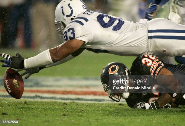Dwight Freeney of the Indianapolis Colts stretches over running back Cedric Benson of the Chicago Bears to recover a fumble during the first quarter...
