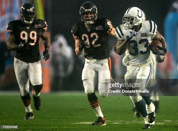 Running back Dominic Rhodes of the Indianapolis Colts carries the ball 36-yards past Tank Johnson and Hunter Hillenmeyer of the Chicago Bears during...