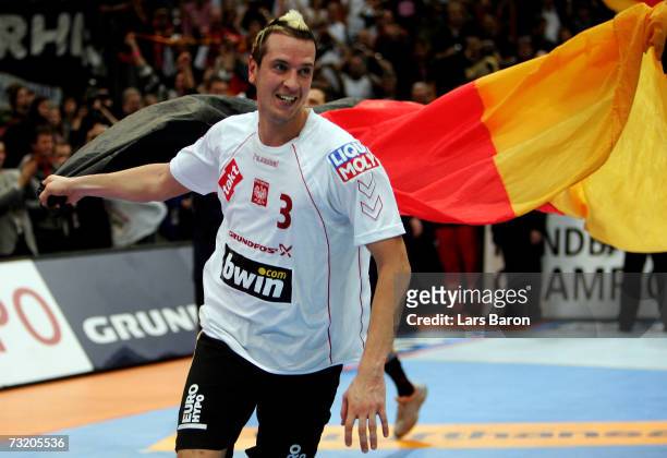 Pascal Hens celebrates with a german flag after winning the IHF World Championship final game between Germany and Poland at the Cologne Arena on...