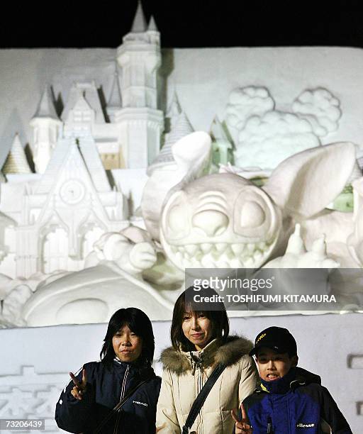Family poses in front of the snow sculpture of the Disney character Stitch at the Odori park in central Sapporo, 05 February 2007. The annual snow...