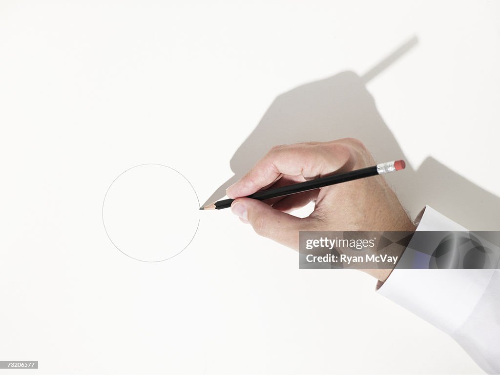 Man drawing circle with pencil, close up of hand, overhead view