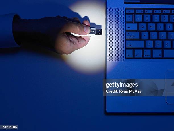 man plugging portable usb hard drive  into laptop, close up of hand, overhead view - festplatte stock-fotos und bilder