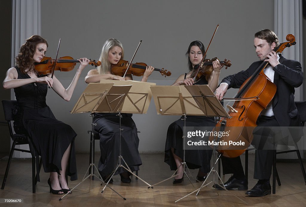 Three people playing violins and one playing cello