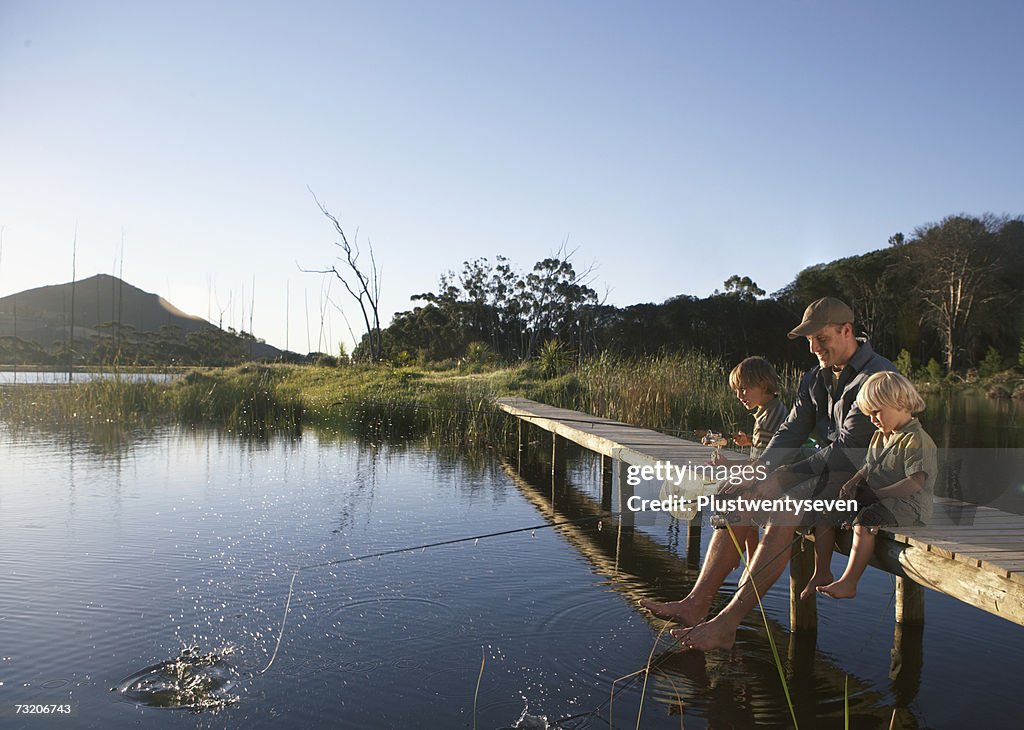 Father and sons (2-4) on jetty, fishing