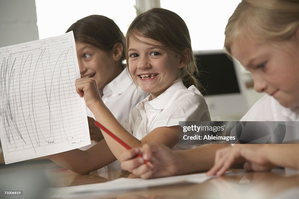 Girl (8-10) showing her paper in classroom