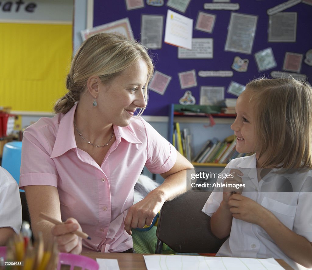 Teacher helping girl (5-7) in classroom