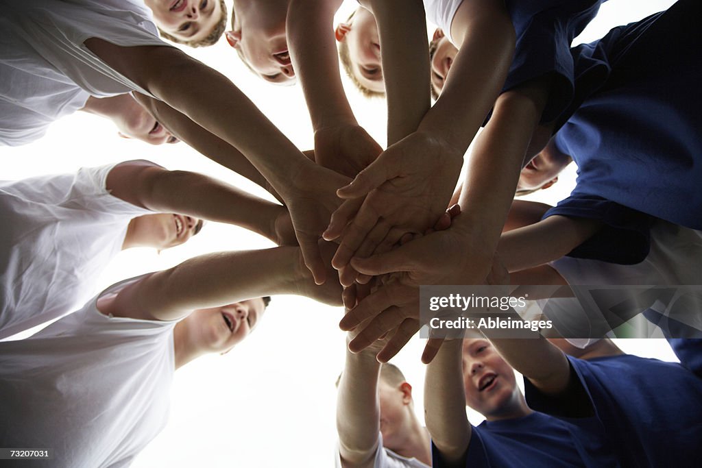 Boys (9-11) on soccer team putting hands in, view from below