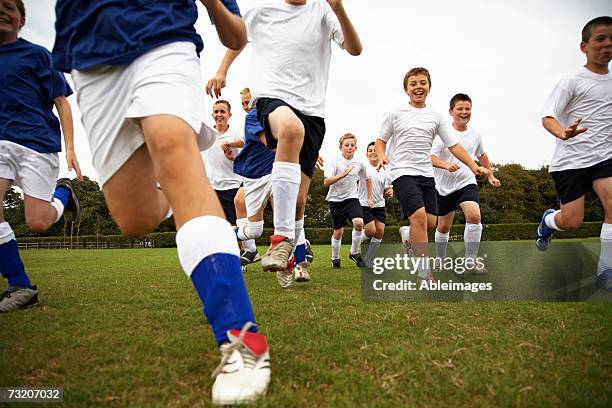 boys (9-11) running on soccer field - jugendfußball stock-fotos und bilder