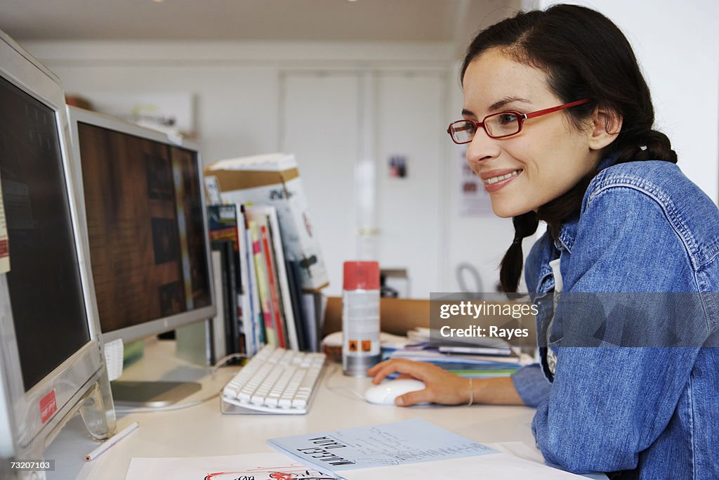 Young female office worker using computer, side view