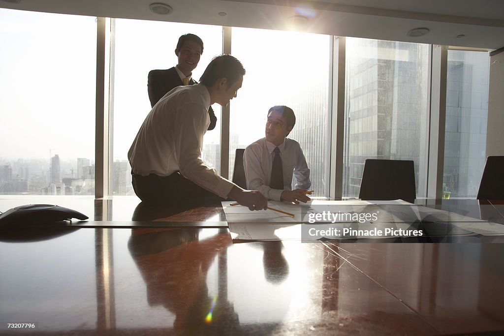 Businessmen looking at blueprint in conference room