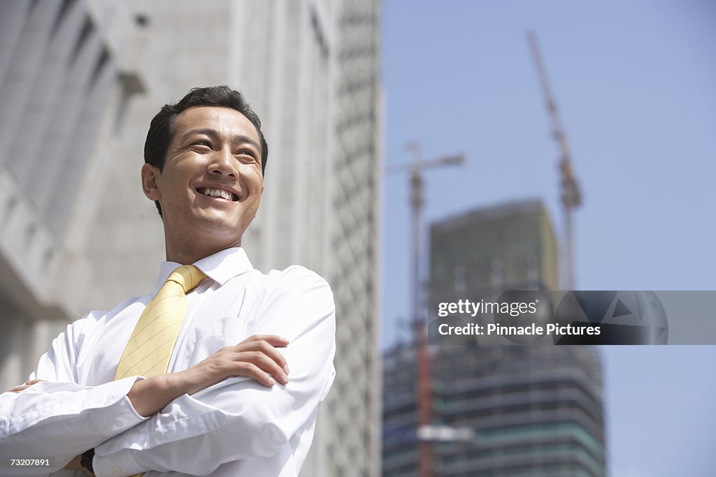 Businessman with arms crossed near office buildings