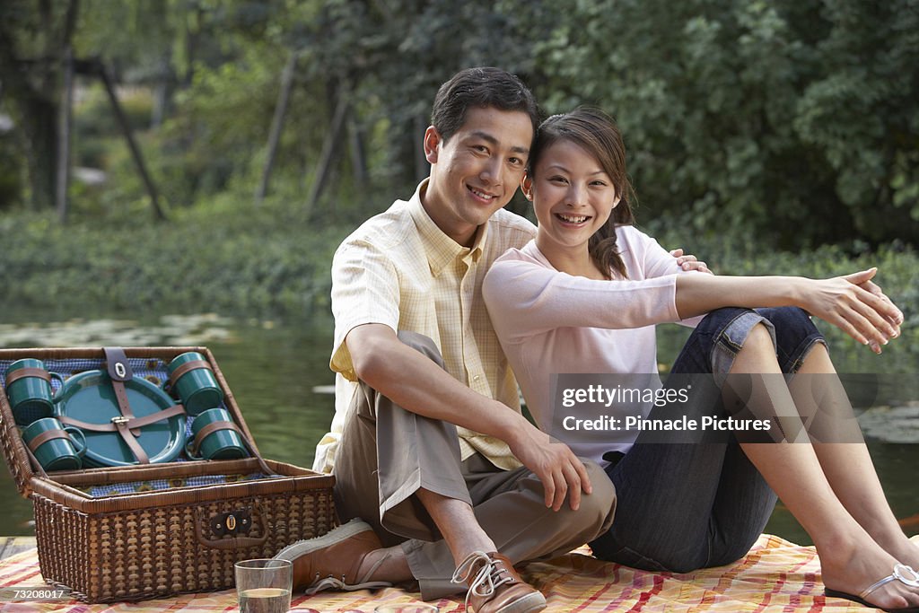 Young couple having picnic by pond, portrait