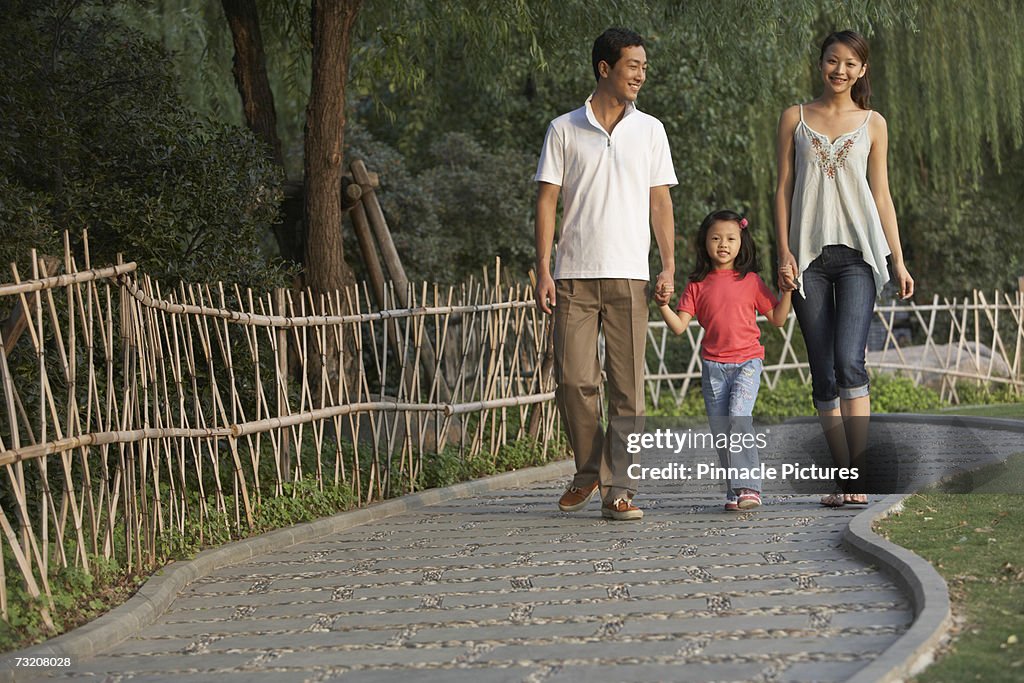 Parents walking with daughter (4-5) in park