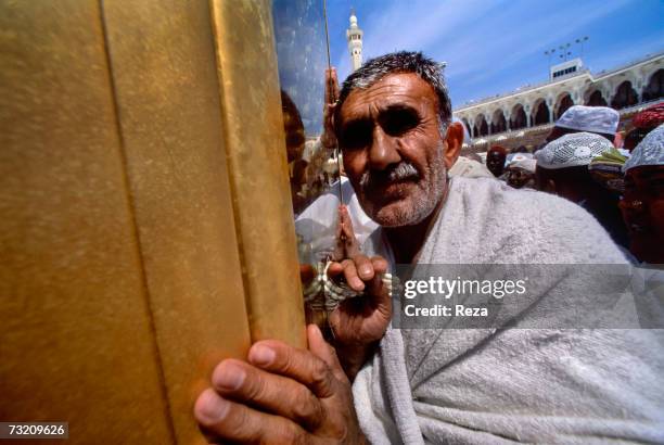 Muslim pilgrim touches the small shrine Maqam Ibrahim, which legend states, holds a stone which retains the permanent footprint of the prophet...