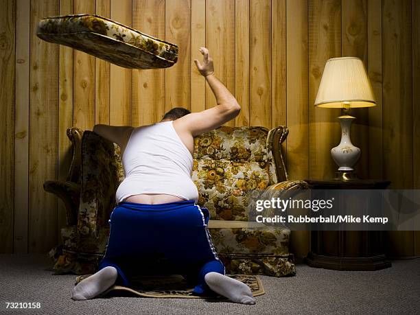 man tossing sofa cushion - under sofa stockfoto's en -beelden