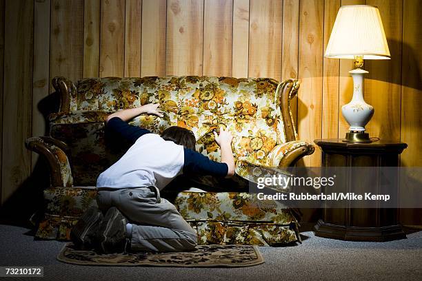 boy searching under sofa cushions - under sofa stockfoto's en -beelden