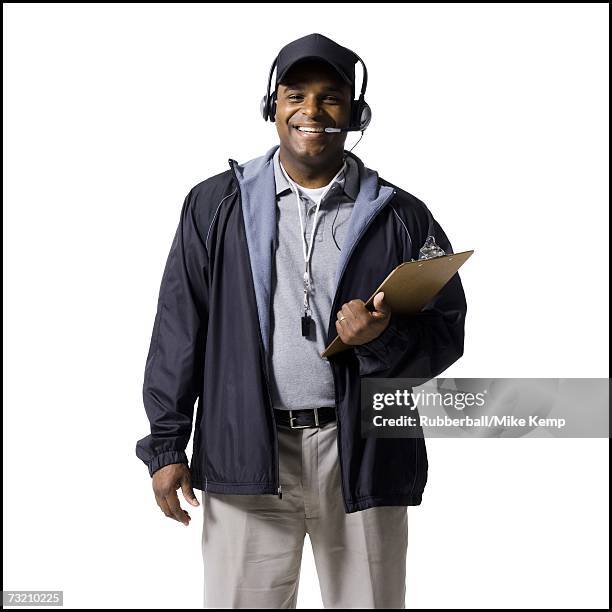 coach with clipboard and headset smiling - american football coach stock-fotos und bilder