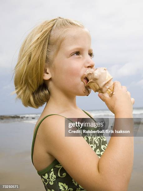 girl with ice cream cone at the beach - girl eating messy ice cream cone stock-fotos und bilder