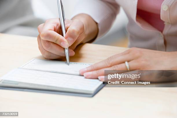 woman writing a cheque - chèque photos et images de collection