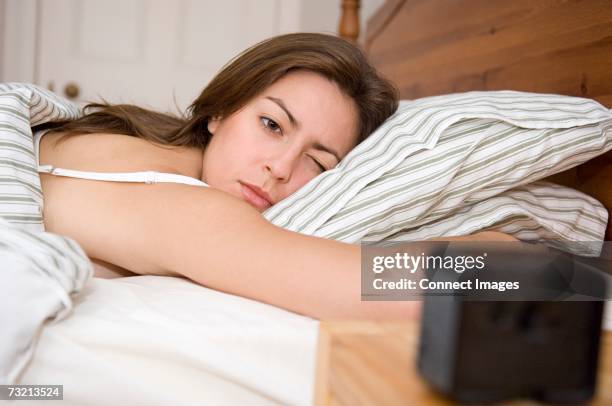 woman lying in bed - alarm clock stock pictures, royalty-free photos & images
