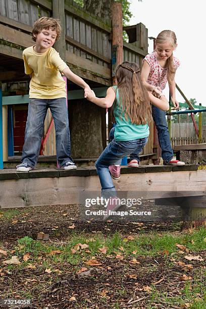 kids pulling friend onto climbing frame - jungle gym stock pictures, royalty-free photos & images