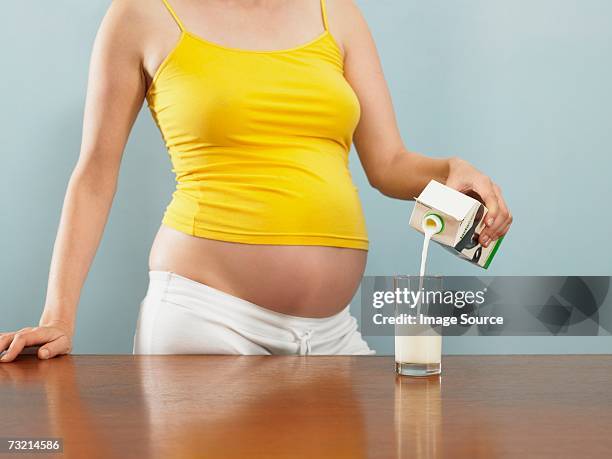 pregnant woman pouring milk - cartón de bebida fotografías e imágenes de stock