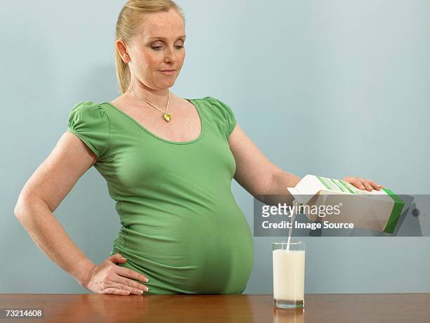 pregnant woman pouring milk - cartón de bebida fotografías e imágenes de stock