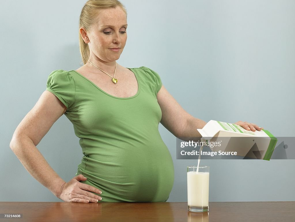 Pregnant woman pouring milk