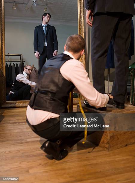tailor adjusting man's trousers, close-up - model crouching stock pictures, royalty-free photos & images