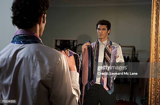 man trying on tie, standing in front of mirror - krawatte stock-fotos und bilder